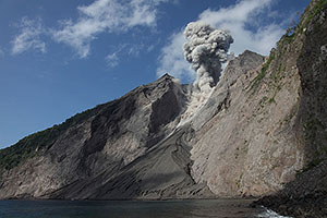 Coastline of Batu Tara volcano with eruption
