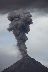 Ash cloud rising into grey sky following explosive eruption of Colima volcano