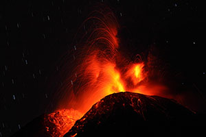 Nighttime eruption of Colima volcano with incandescent blocks thrown from crater