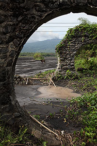 Old bridge remains with Dukono volcano framed thereby