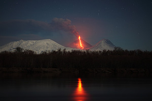 Kliuchevskoi volcano (Kluchevskoy, Klyuchevskaya Sopka) erupting with reflection in Kamchatka River