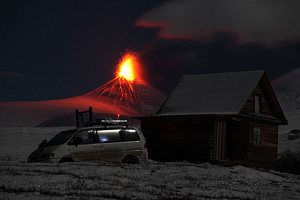 Mountain hut with eruption of Kliuchevskoi volcano behind