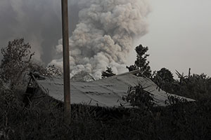 Hut with ash on roof and pyroclastic flow behind, Sinabung Volcano
